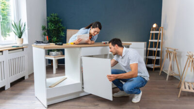 Multiracial couple, Japanese woman and Caucasian man, together assembling kitchen cabinets in their new apartment