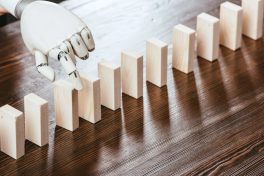 robotic hand picking wooden brick from row of blocks on desk with copy space