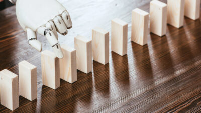 robotic hand picking wooden brick from row of blocks on desk with copy space