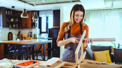 Young woman wearing an apron and assembling furniture at home. DIY concept