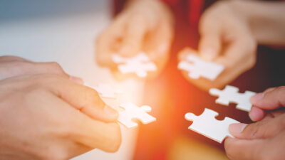 The hands of a variety of people including the Asian jigsaw puzzle And gather parts to find suitable partners to support teamwork to find common problem solving concepts, close-up perspectives