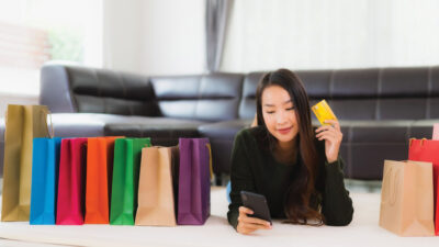 Portrait beautiful young asian woman with shopping bag and credit card with mobile phone for online shopping at home