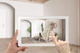 Augmented reality concept. Hand holding tablet with AR application used to simulate furniture and design products in empty interior with parquet, modern living room with sofa