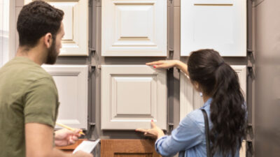 Young woman looks a cabinetry display in home improvement store. A male salesperson is helping her.