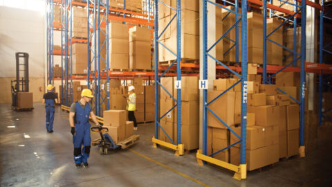 Retail Warehouse full of Shelves with Goods in Cardboard Boxes, Workers Scan and Sort Packages, Move Inventory with Pallet Trucks and Forklifts. Product Distribution Delivery Center.